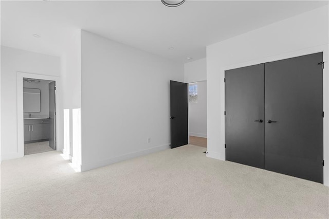 unfurnished bedroom featuring light carpet, ensuite bath, and a closet