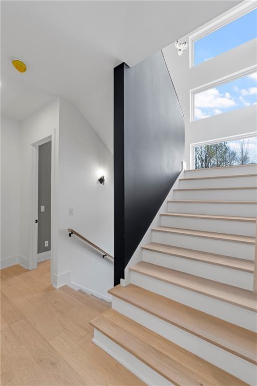 stairs featuring hardwood / wood-style flooring and vaulted ceiling