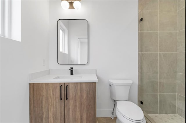 bathroom with tiled shower, vanity, and toilet