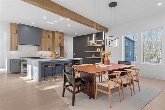 dining space with beam ceiling and light hardwood / wood-style flooring