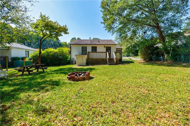 back of property with a lawn, a deck, and an outdoor fire pit