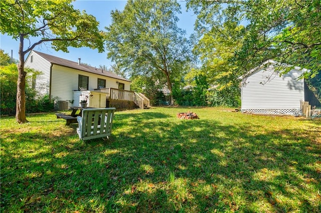 view of yard featuring a wooden deck, central air condition unit, and an outdoor fire pit