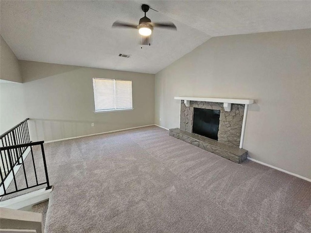 unfurnished living room featuring vaulted ceiling, a stone fireplace, carpet, ceiling fan, and a textured ceiling