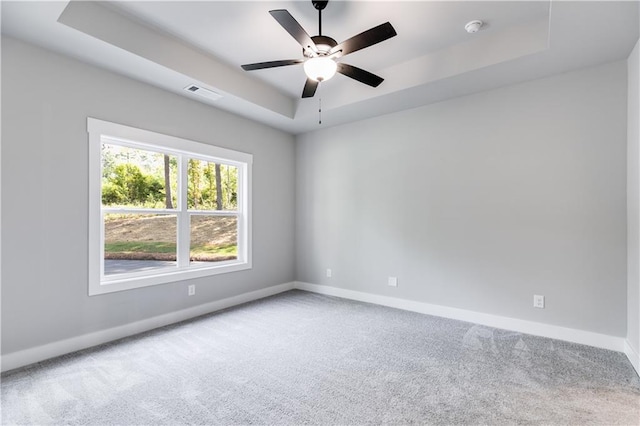 spare room featuring a tray ceiling, ceiling fan, and carpet floors