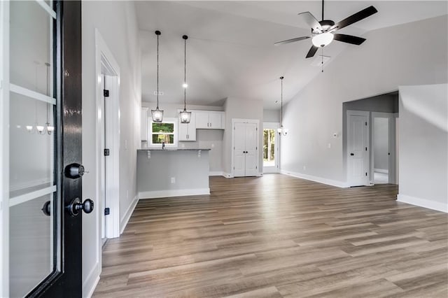 unfurnished living room with hardwood / wood-style floors, ceiling fan, and vaulted ceiling