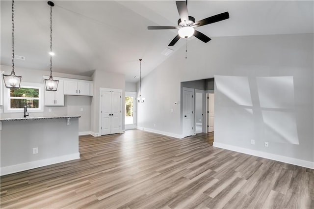 unfurnished living room with a wealth of natural light, high vaulted ceiling, light hardwood / wood-style flooring, and ceiling fan