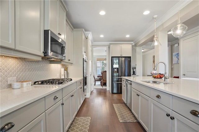 kitchen with stainless steel appliances, a sink, ornamental molding, light countertops, and decorative light fixtures