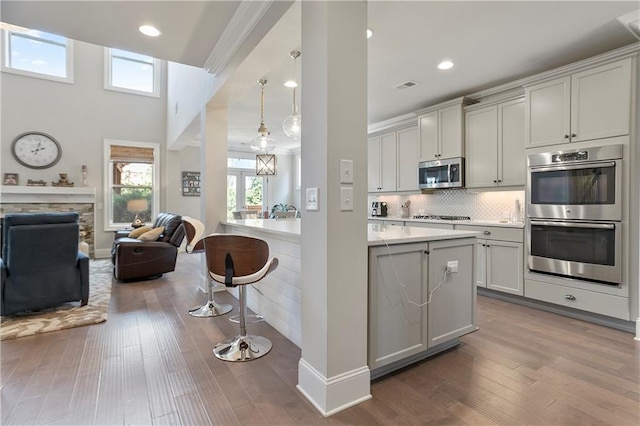 kitchen with appliances with stainless steel finishes, a breakfast bar area, open floor plan, dark wood-style flooring, and recessed lighting