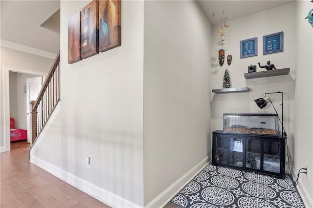 staircase featuring baseboards, ornamental molding, and wood finished floors