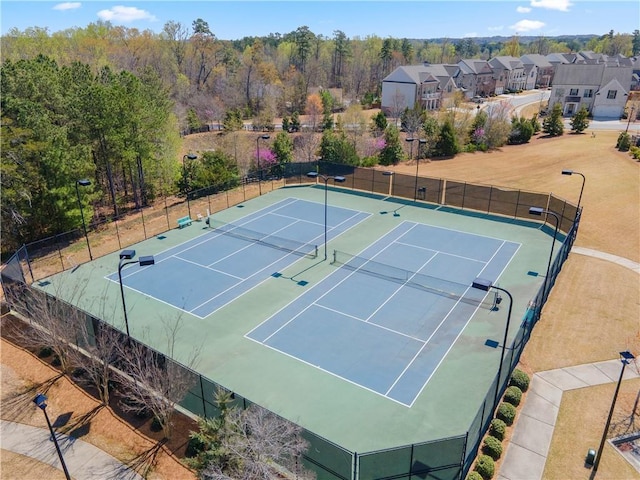 view of tennis court with fence, community basketball court, and a residential view