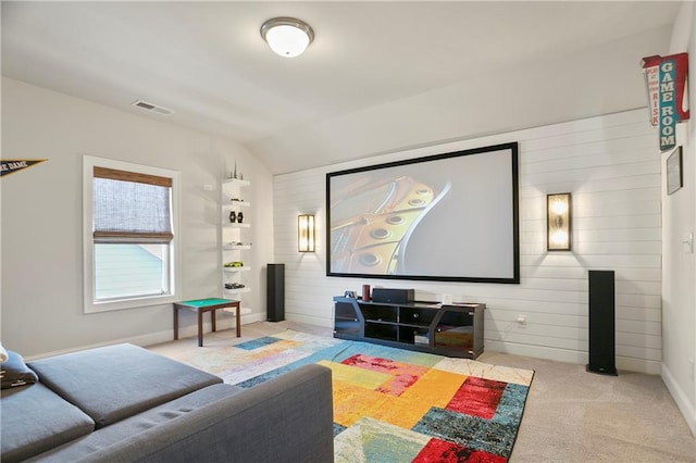 home theater room with vaulted ceiling, carpet floors, wood walls, and baseboards
