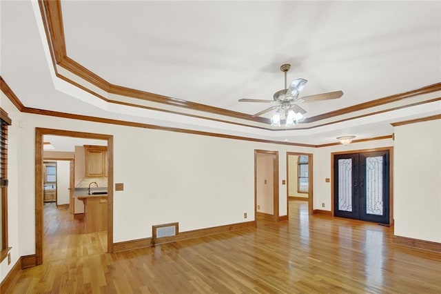 spare room with french doors, a raised ceiling, visible vents, light wood-type flooring, and baseboards