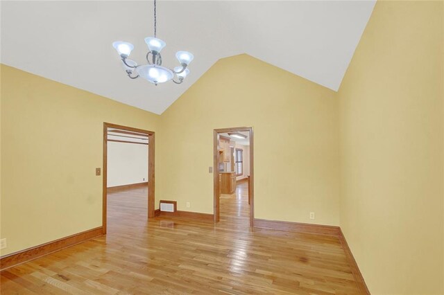 unfurnished room with high vaulted ceiling, visible vents, an inviting chandelier, and wood finished floors