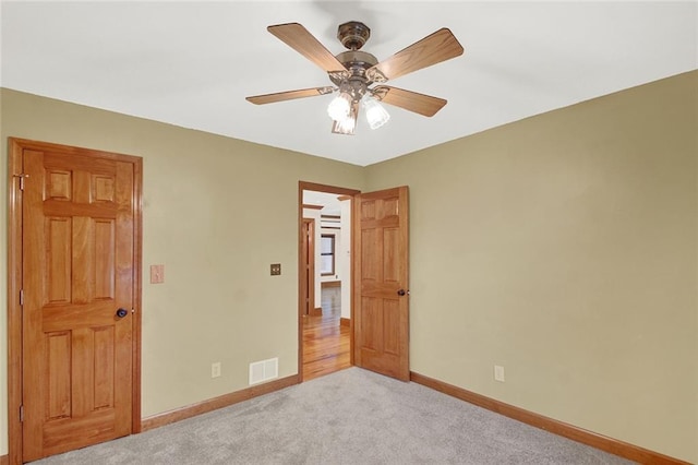 unfurnished bedroom with light carpet, baseboards, visible vents, and ceiling fan