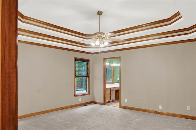 spare room featuring ornamental molding, a raised ceiling, a ceiling fan, and light colored carpet