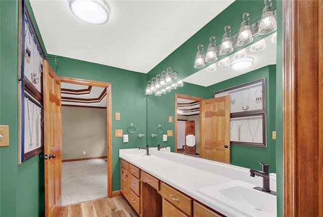 full bathroom with double vanity, baseboards, a sink, and wood finished floors