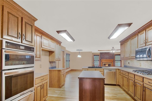 kitchen with a center island, stainless steel appliances, light countertops, a sink, and a peninsula