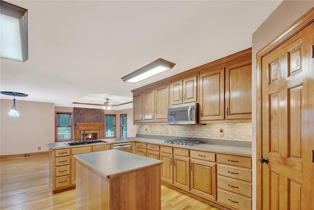 kitchen with pendant lighting, stainless steel appliances, light countertops, a sink, and a peninsula