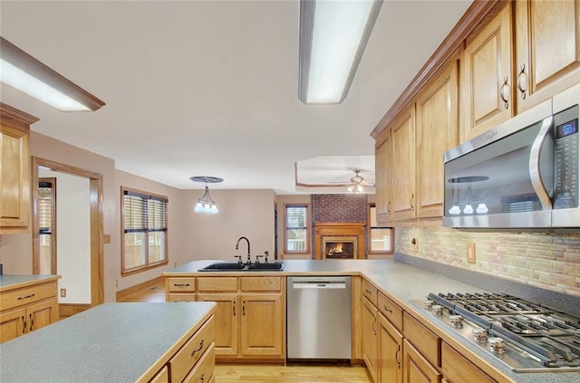 kitchen featuring hanging light fixtures, stainless steel appliances, a sink, and light countertops