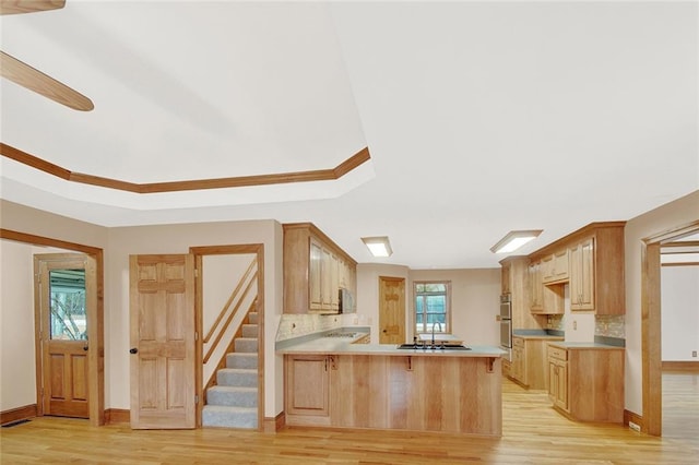 kitchen with a peninsula, light brown cabinets, light countertops, and a sink