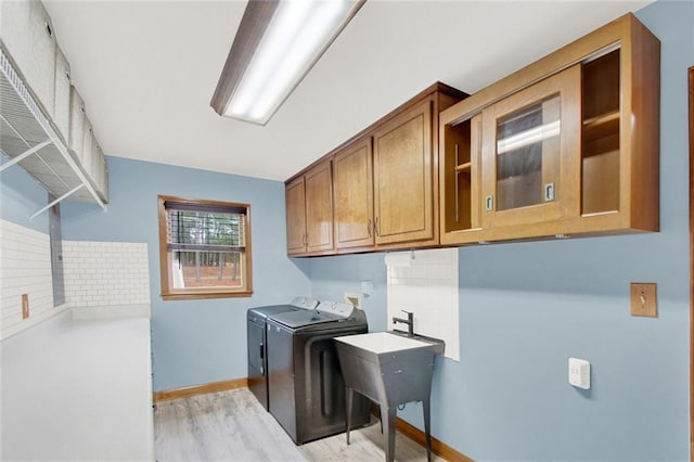 laundry room featuring light wood-type flooring, independent washer and dryer, cabinet space, and baseboards