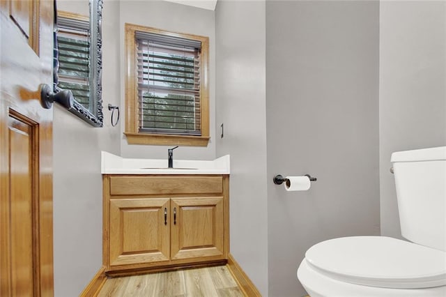 bathroom with toilet, baseboards, wood finished floors, and vanity