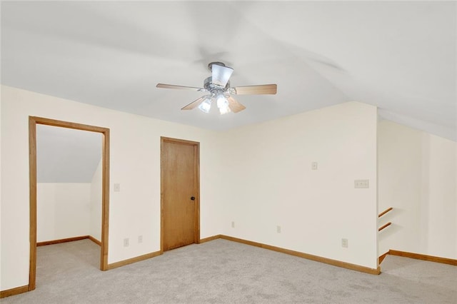 unfurnished bedroom with a closet, light carpet, vaulted ceiling, and baseboards