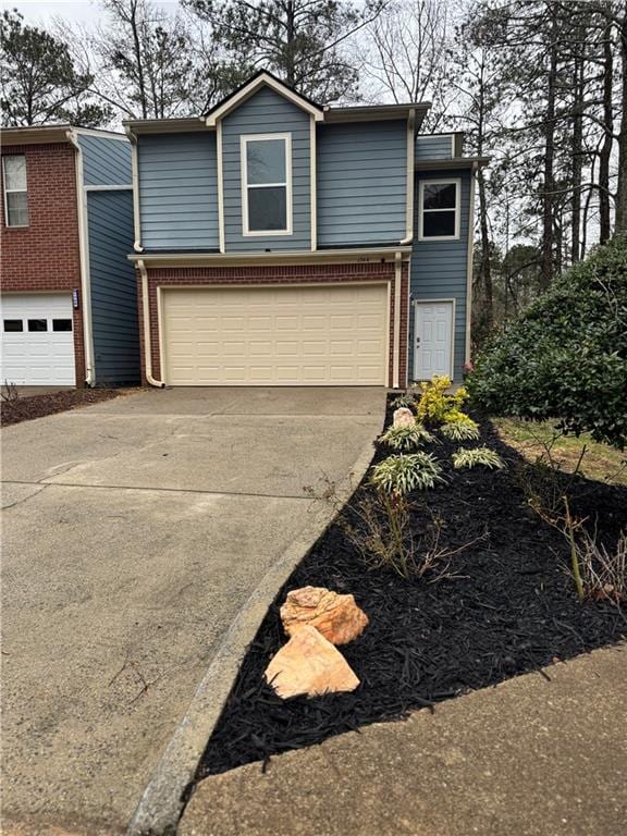 view of front facade with a garage, driveway, and brick siding