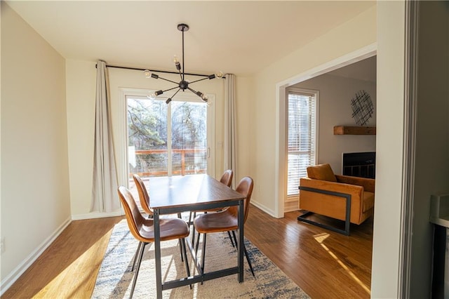 dining area with a fireplace, baseboards, and wood finished floors