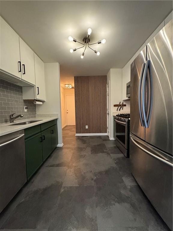 kitchen featuring tasteful backsplash, white cabinets, appliances with stainless steel finishes, light countertops, and a sink