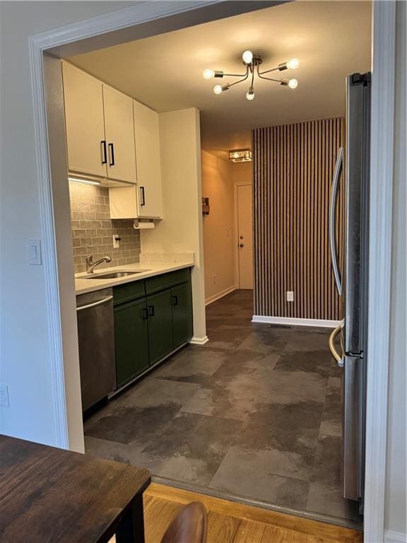 kitchen with stainless steel appliances, tasteful backsplash, light countertops, white cabinets, and a sink