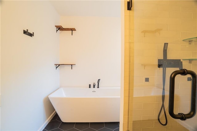 full bath featuring tile patterned flooring, tiled shower, a freestanding bath, and baseboards