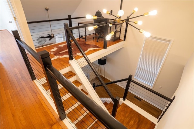 staircase with a chandelier and wood finished floors