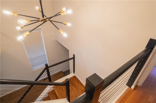 staircase with baseboards, a chandelier, and wood finished floors