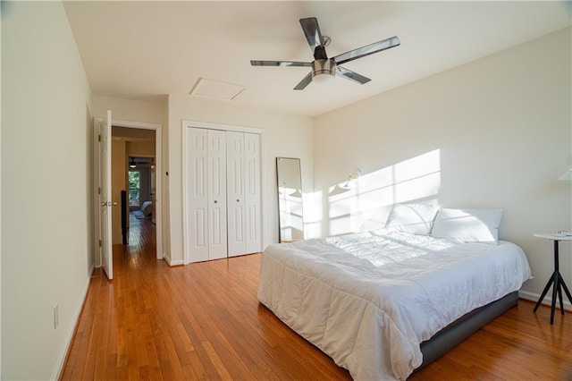 bedroom featuring hardwood / wood-style floors, a closet, attic access, and baseboards