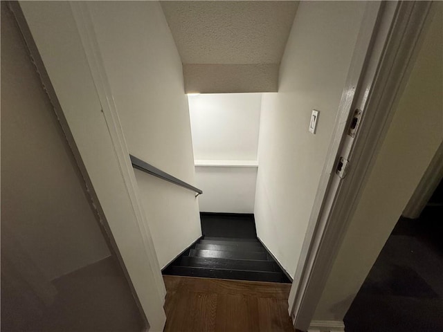 staircase featuring a textured ceiling and wood finished floors