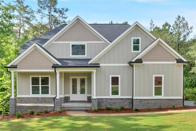 view of front of house featuring board and batten siding, a front lawn, french doors, and roof with shingles