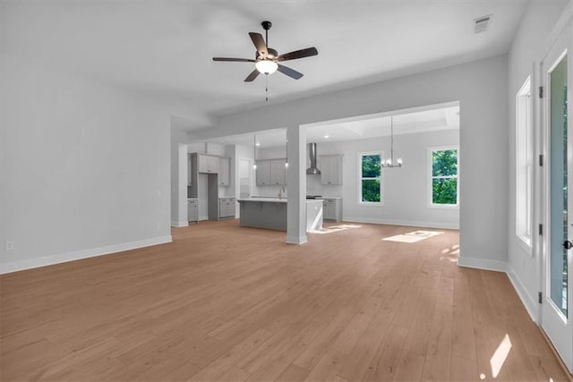 unfurnished living room with light wood-style floors, baseboards, a ceiling fan, and a chandelier