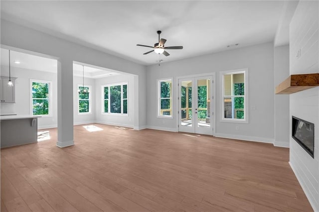 unfurnished living room featuring a ceiling fan, light wood finished floors, and baseboards