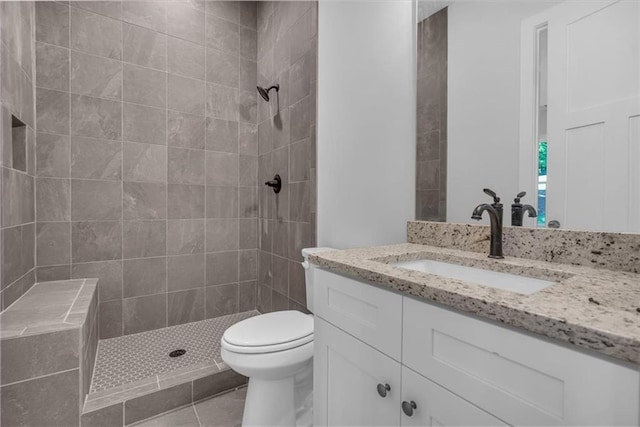 bathroom with a tile shower, vanity, toilet, and tile patterned flooring