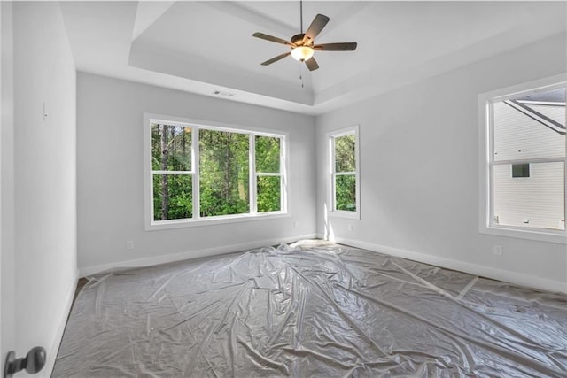 unfurnished room featuring baseboards, a ceiling fan, and a tray ceiling