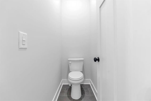 bathroom with toilet, baseboards, and tile patterned flooring