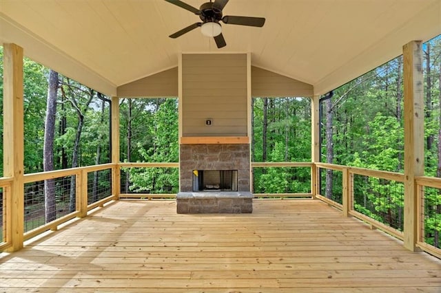 deck with an outdoor stone fireplace and a ceiling fan