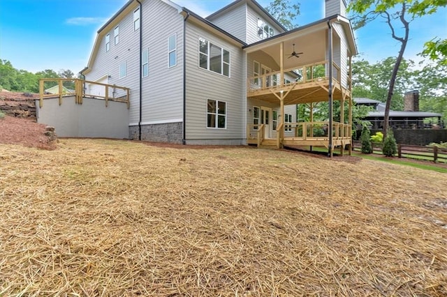 rear view of house with a ceiling fan, a deck, a chimney, a balcony, and fence