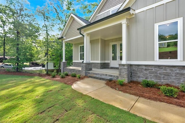 view of side of property featuring board and batten siding, a lawn, stone siding, and french doors
