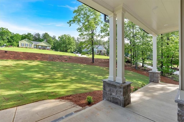 view of grassy yard with covered porch and view of wooded area