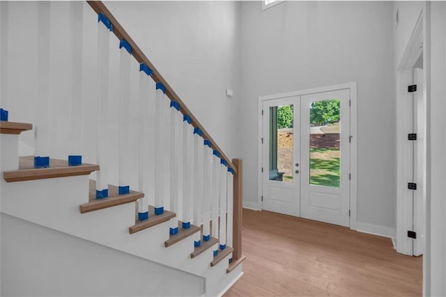 foyer featuring wood finished floors, french doors, stairway, a high ceiling, and baseboards