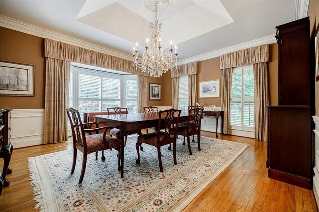 3030 Spalding Dr, Sandy Springs, GA 30350 - dining space featuring a chandelier, a tray ceiling, light wood-style floors, a wainscoted wall, and crown molding