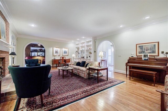 3030 Spalding Dr, Sandy Springs, GA 30350 - living area with arched walkways, a brick fireplace, crown molding, light wood-style flooring, and recessed lighting