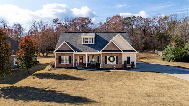 craftsman-style home with covered porch, concrete driveway, brick siding, and a front yard